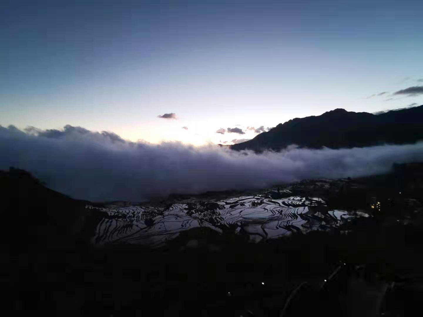 Terraced rice fields at Duoyishu, with reflective water and mist along the mountain slopes
