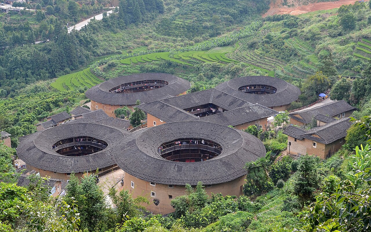 Five Tianluokeng earthen houses, including a square building and round roof forms, among green terraced slopes