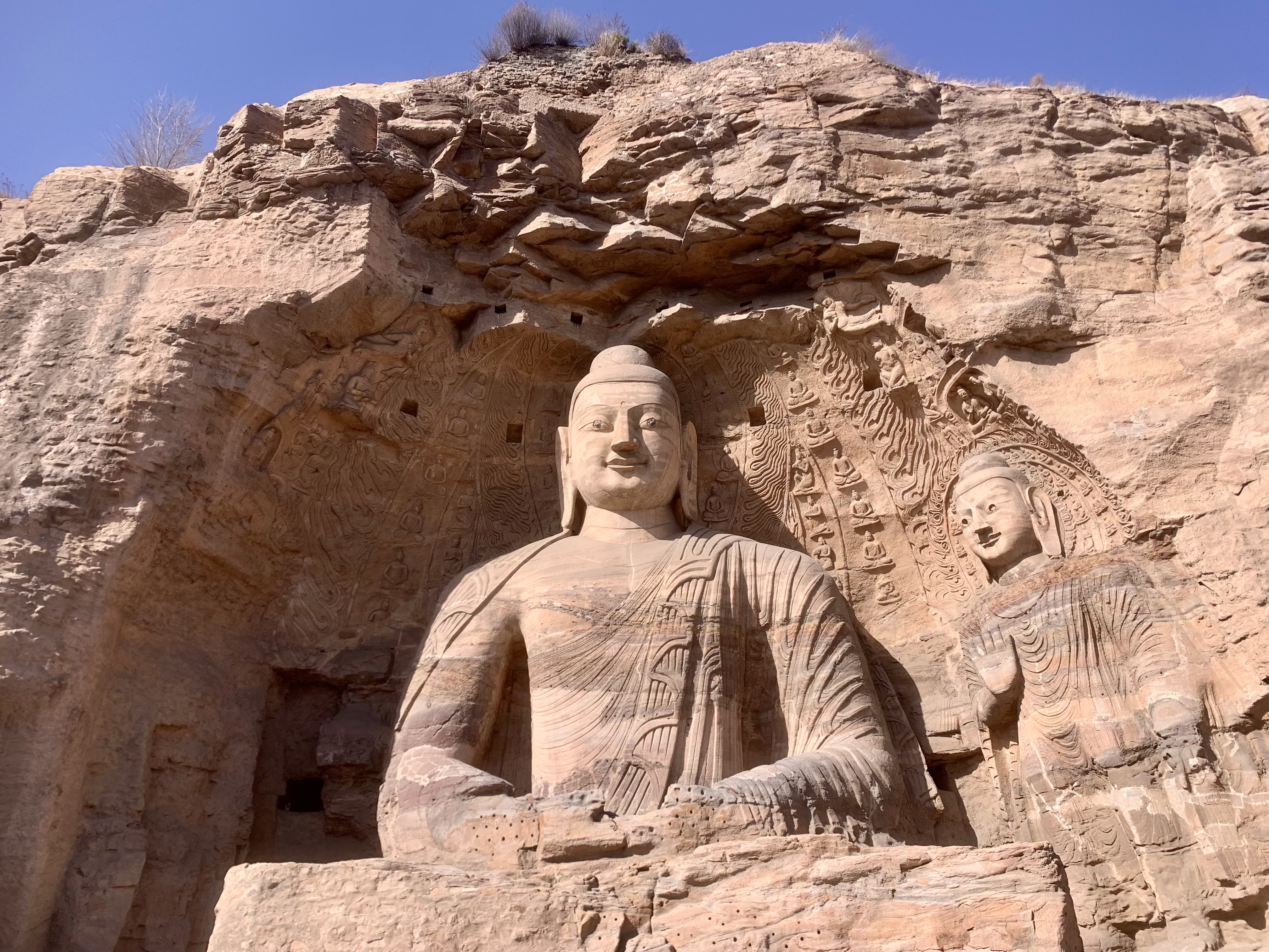 Cave 20 at Yungang with a large seated Buddha, patterned robe and surrounding carved cliff